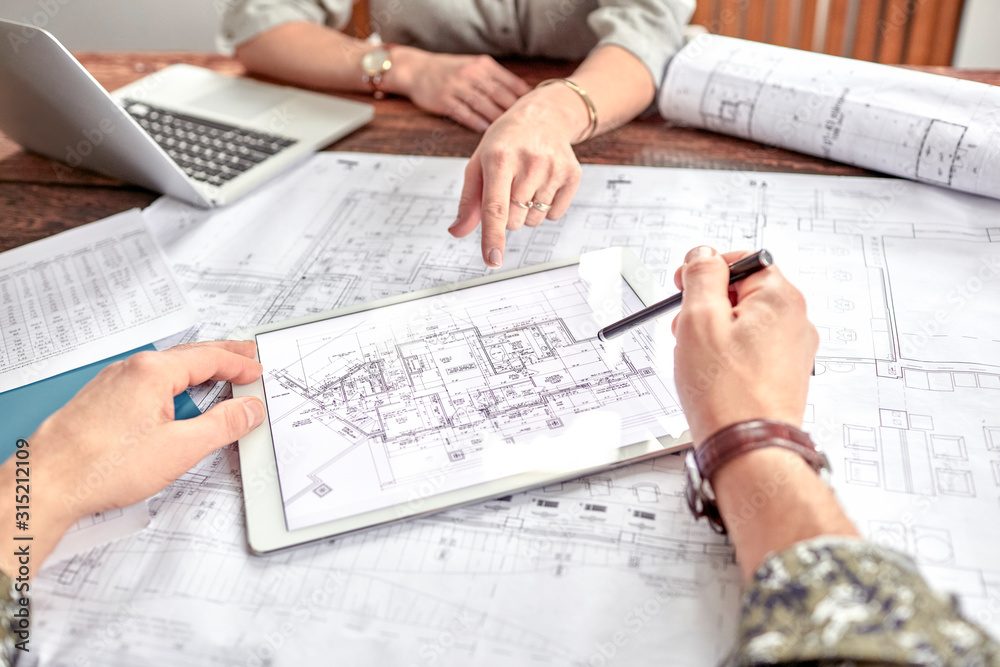 Draftsman and client reviewing residential plans at a table