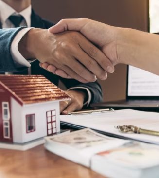 Client and draftsman shaking hands over house plans